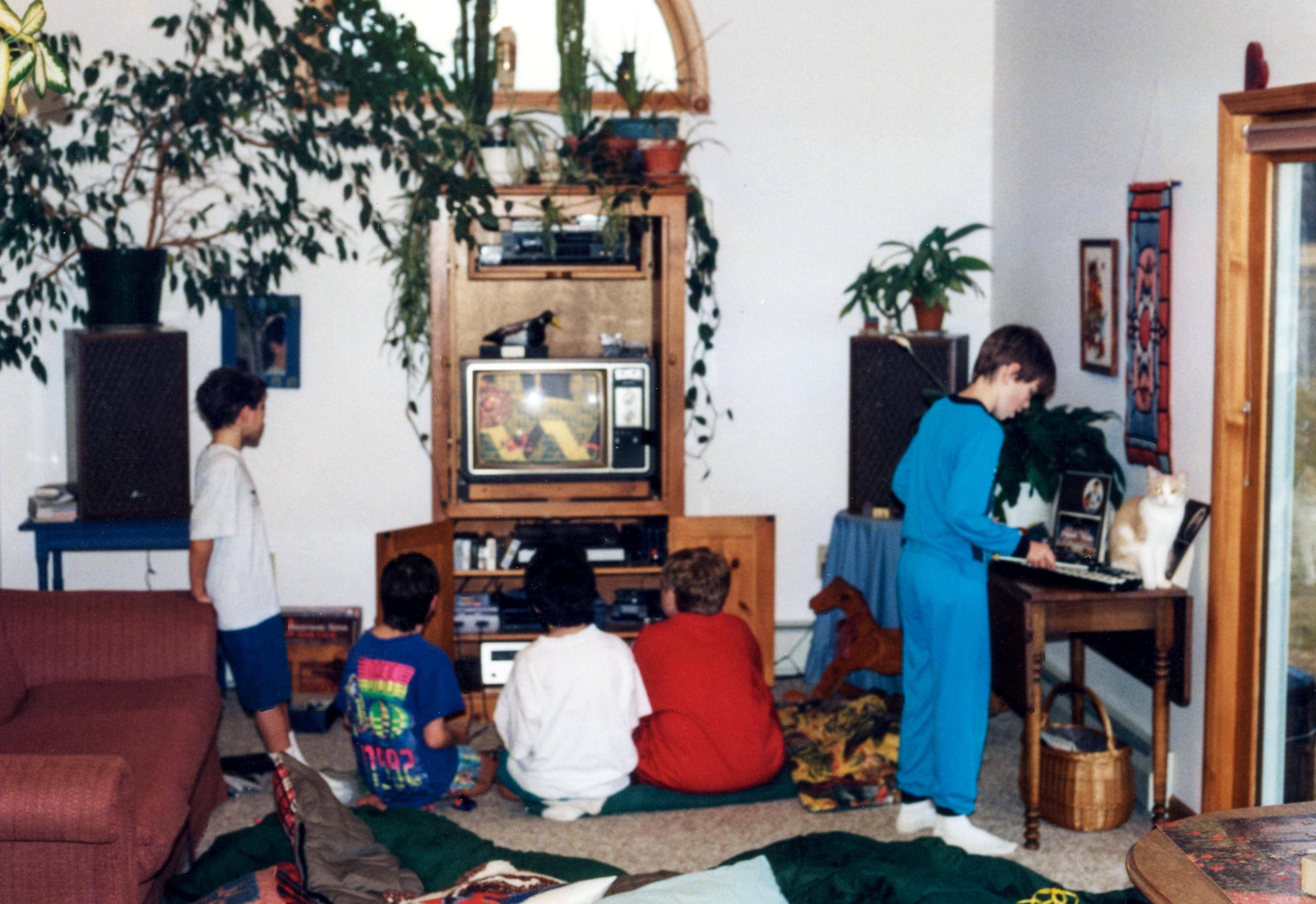 90s living room, kid at keyboard, others watching TV